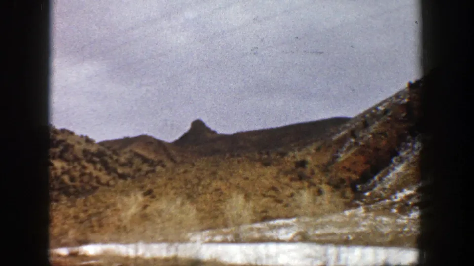 A 1961 Aspen-area landscape frame shows brown mountain terrain, scattered snow, scrub vegetation, and the soft color of 8mm film.