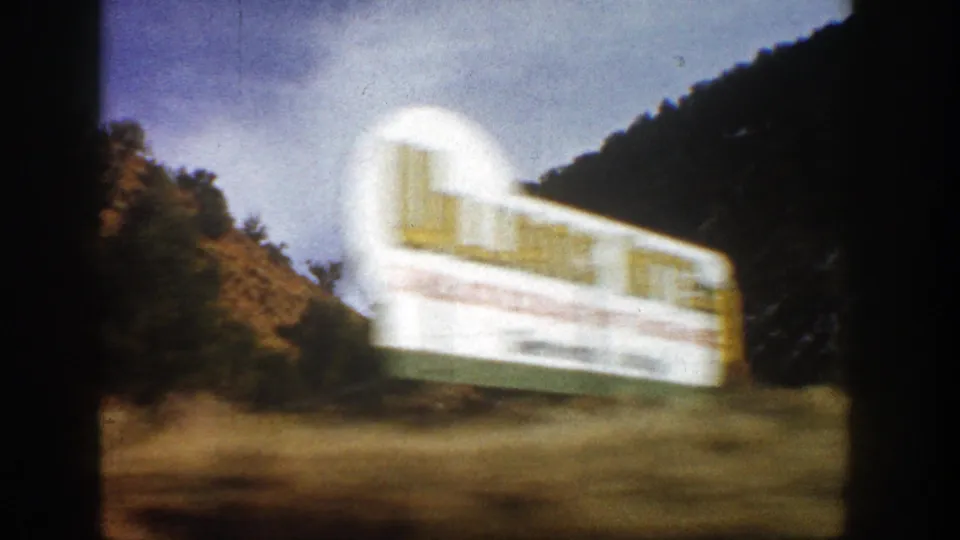 A large white truck or trailer blurs past the camera on a mountain road near Aspen, Colorado, in 1961 8mm footage.