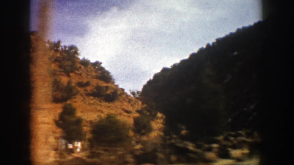 Final 1961 8mm frame shows rocky canyon walls, trees, and a shaded mountain slope near Aspen, Colorado.