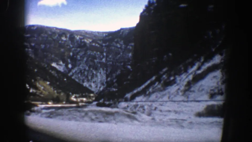 1961 Colorado home-movie view of a snow-lined canyon and river bend framed by the edge of a vehicle window.