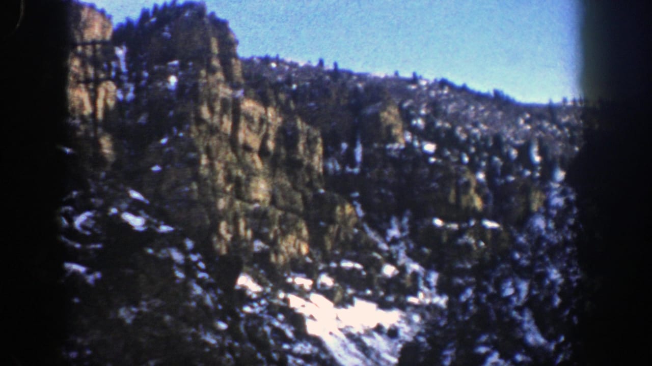 Snowy rocky mountain slope beneath a clear blue sky.