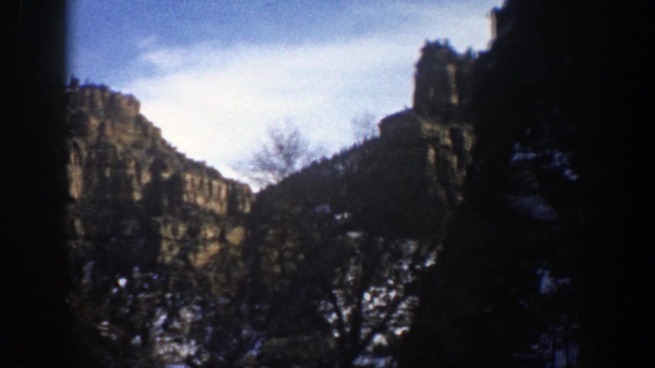 Snow-dusted rocky mountain peaks seen through dark frame edges.