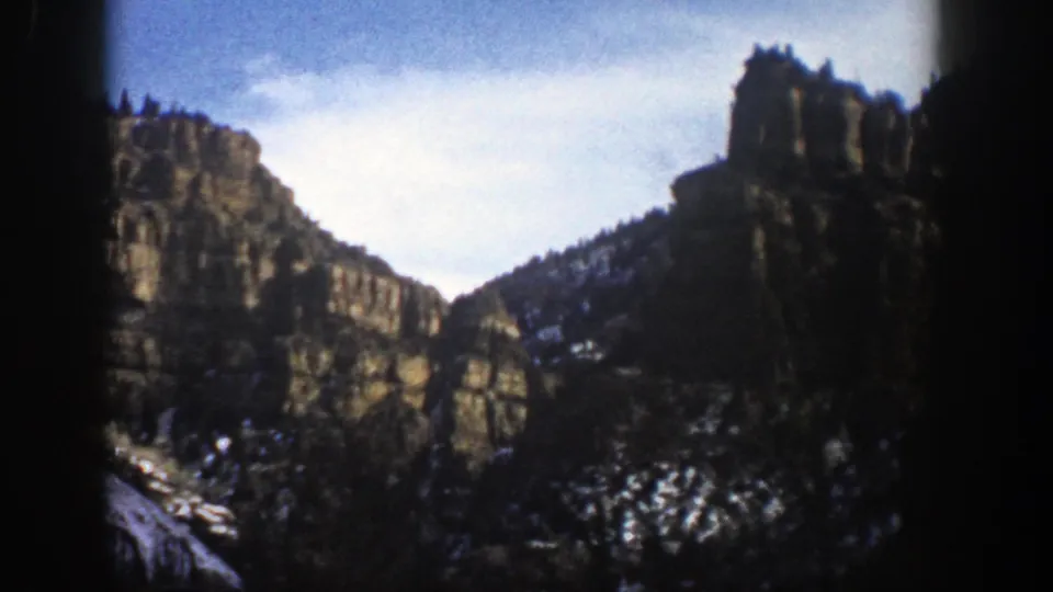 End frame of the Aspen mountain pan, with rocky formations, snow patches, dark tree shapes, and pronounced 8mm frame edges.