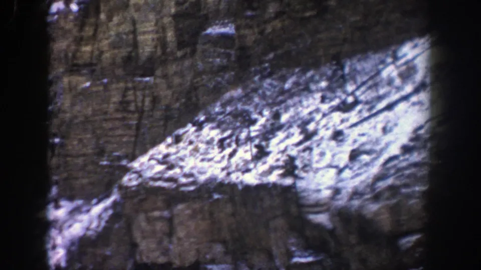 Rocky Colorado cliff face with snow patches, filmed from a moving car in the Aspen area in 1961.
