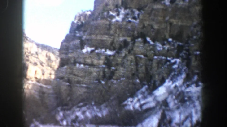 Aspen-area mountain canyon with snow-dusted rock slopes and bright daylight, captured from a moving car in 1961.