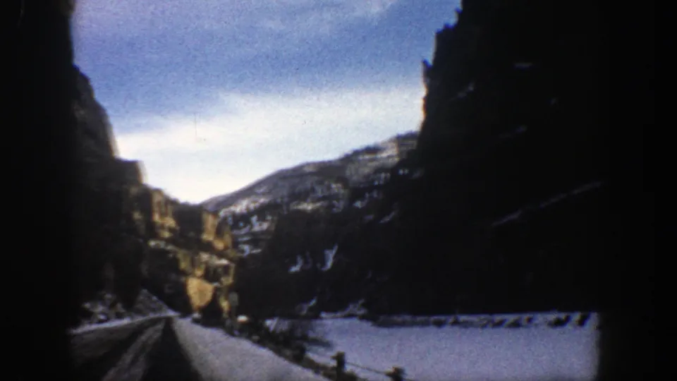 Forward-facing 8mm travel view near Aspen, Colorado, showing a winter road through cliffs and snow-covered terrain.