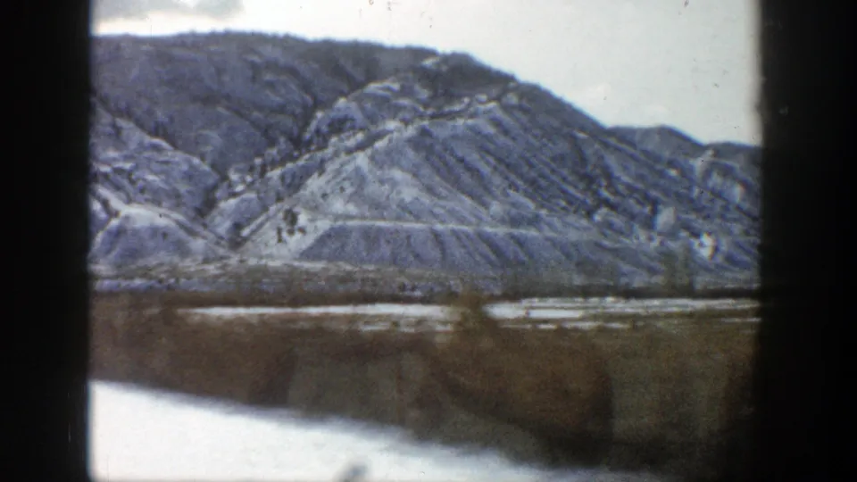 Moving 8mm view from a train near Aspen, Colorado, showing a rugged ridge, pale snow patches, and a blurred foreground.
