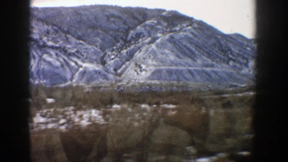 1961 Aspen-area home-movie view of a snow-dusted rocky mountain slope through a car window.