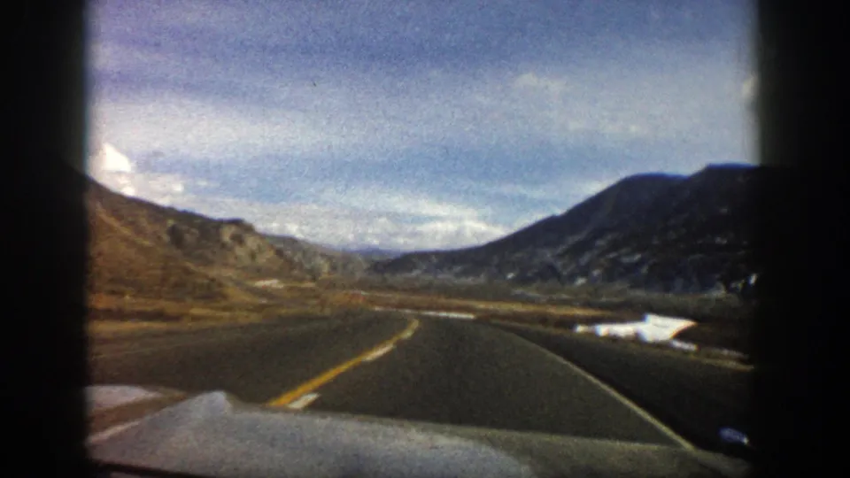 1961 Aspen, Colorado home-movie view from inside a moving car on a two-lane road through a mountain valley.