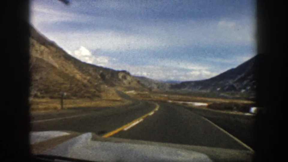 1961 passenger-view road footage in the Aspen, Colorado area, showing a curved highway, hillsides, and distant mountains.