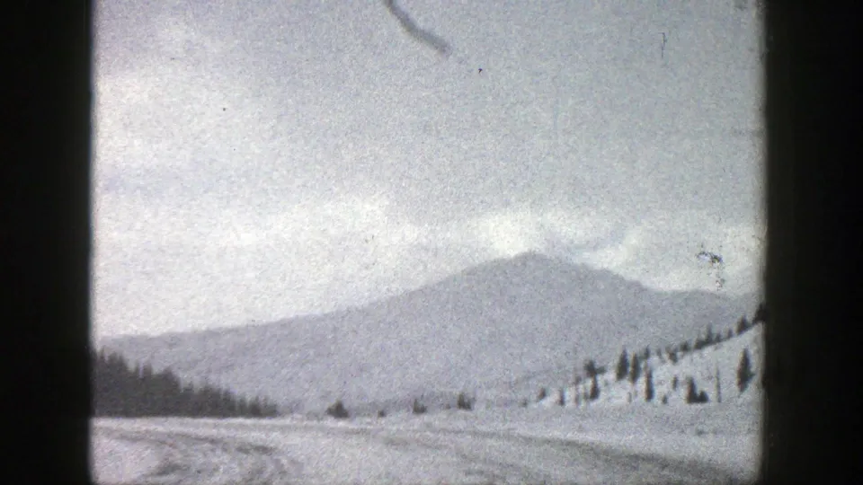 Late-frame view of the snow-covered road, open valley and distant mountain in 1961 Aspen home-movie footage.