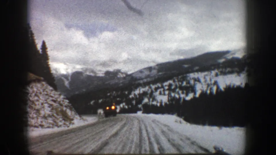 1961 Aspen 8mm frame of a snow-covered mountain road as a vehicle with headlights approaches in the distance.
