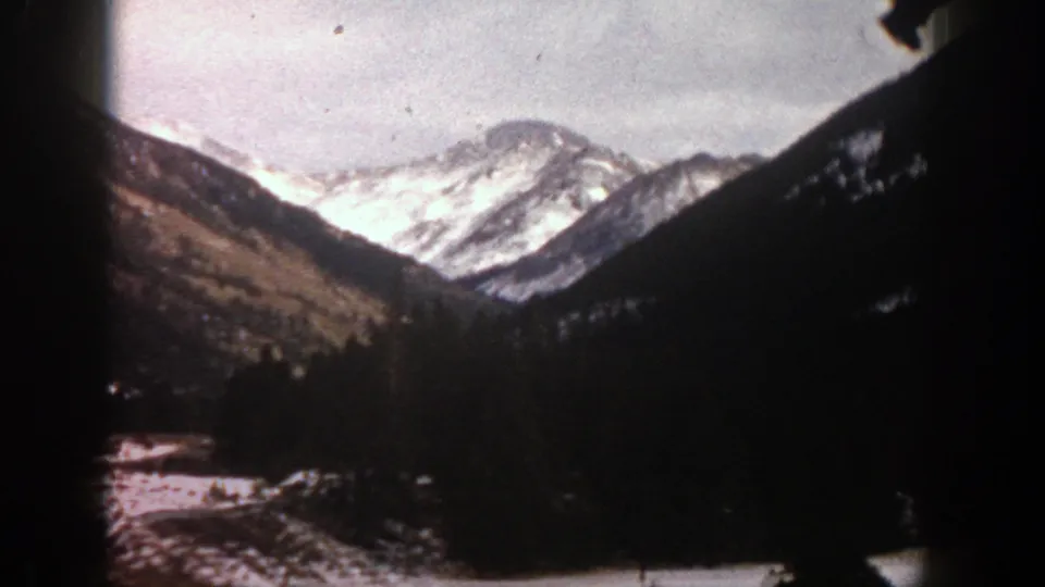 1961 Aspen mountain view with a snow-covered peak framed by darker slopes and 8mm gate edges.