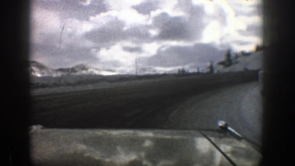 The car continues along a snow-lined mountain road in the Aspen, Colorado footage, with low clouds over the ridge ahead.