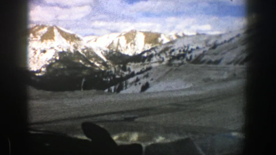 1961 Aspen, Colorado view of bright snowfields, mountain peaks, and trees framed by the car interior.