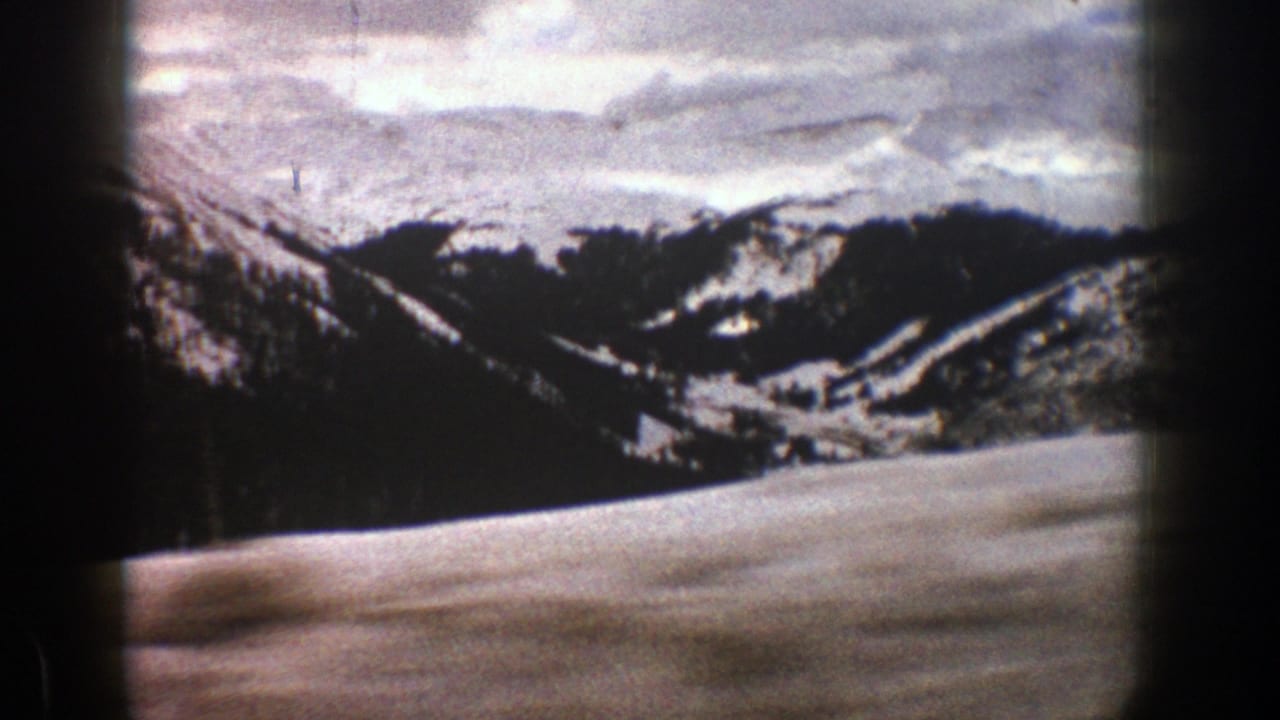 Snowy mountain valley seen through a dark car-window edge.