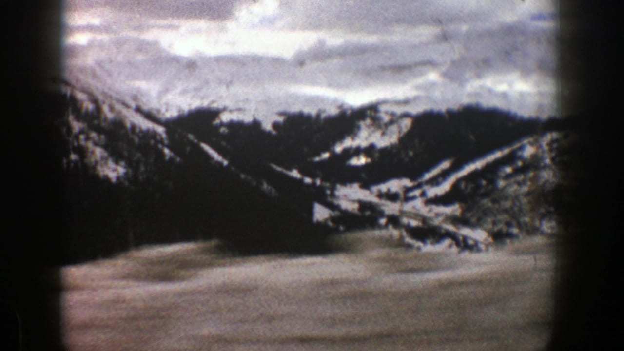 Snow-covered ridges and forest viewed from a moving car.