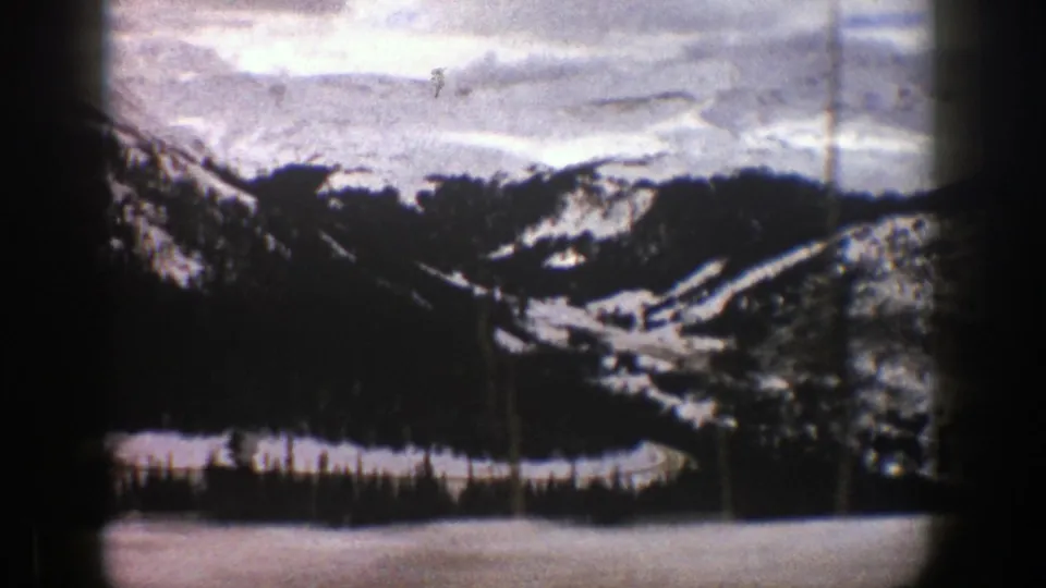Aspen, Colorado winter travel frame with snowy foreground, evergreen forest, and distant ridges seen through darkened 8mm frame edges.