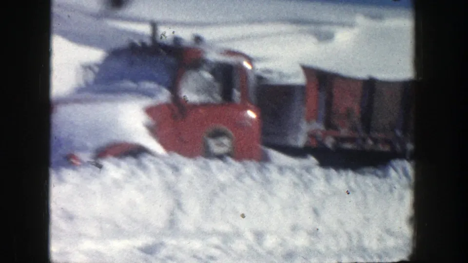 Soft, handheld 1961 Aspen frame showing the red truck cab and rear section partly obscured by piled snow.