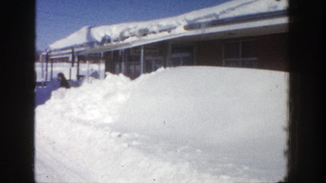 High snowbank outside a brick building with a person near the entrance.