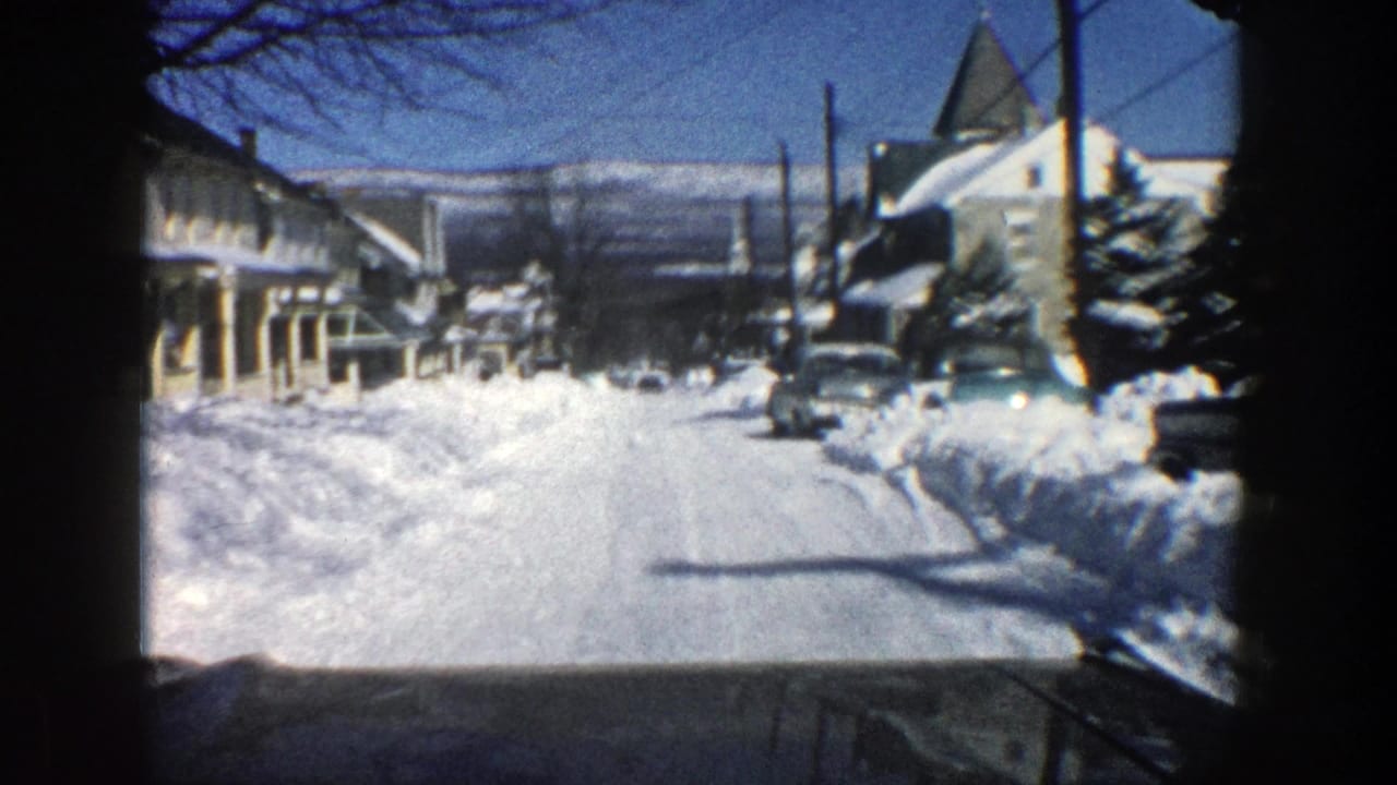 Snow-covered residential street seen from inside a moving vehicle.