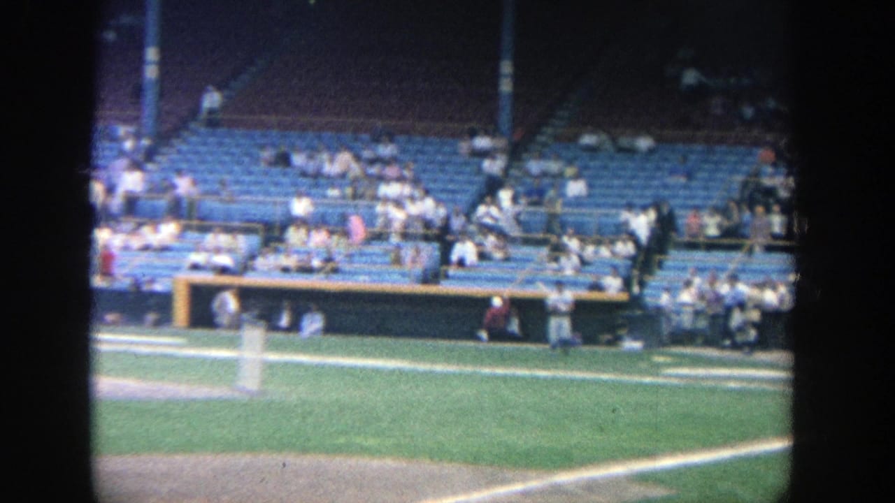 Stadium seating and field edge with spectators gathered behind the baseball play area.