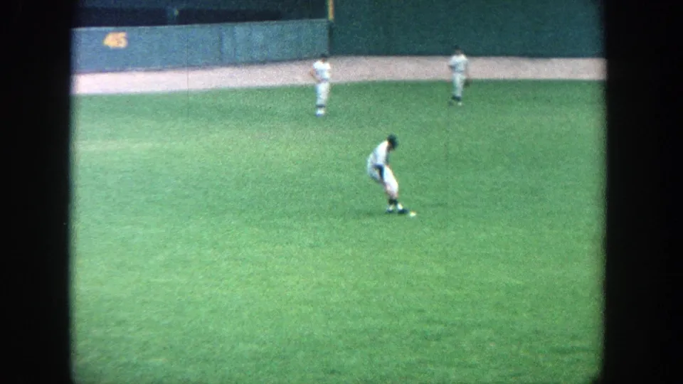1964 Yankee Stadium view from the stands, with players in white uniforms positioned across the green outfield.
