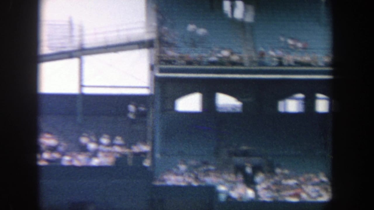1964 Yankee Stadium spectator view showing upper seating, stadium structure, railings, and fans gathered below.