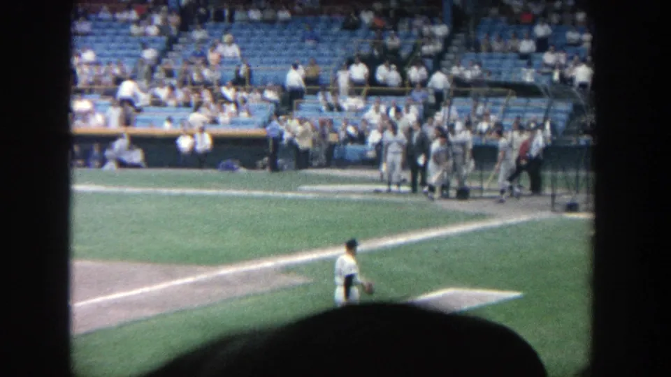 Yankee Stadium frame from the supplied 1964 clip, with a pitcher on the field and people gathered near the dugout.
