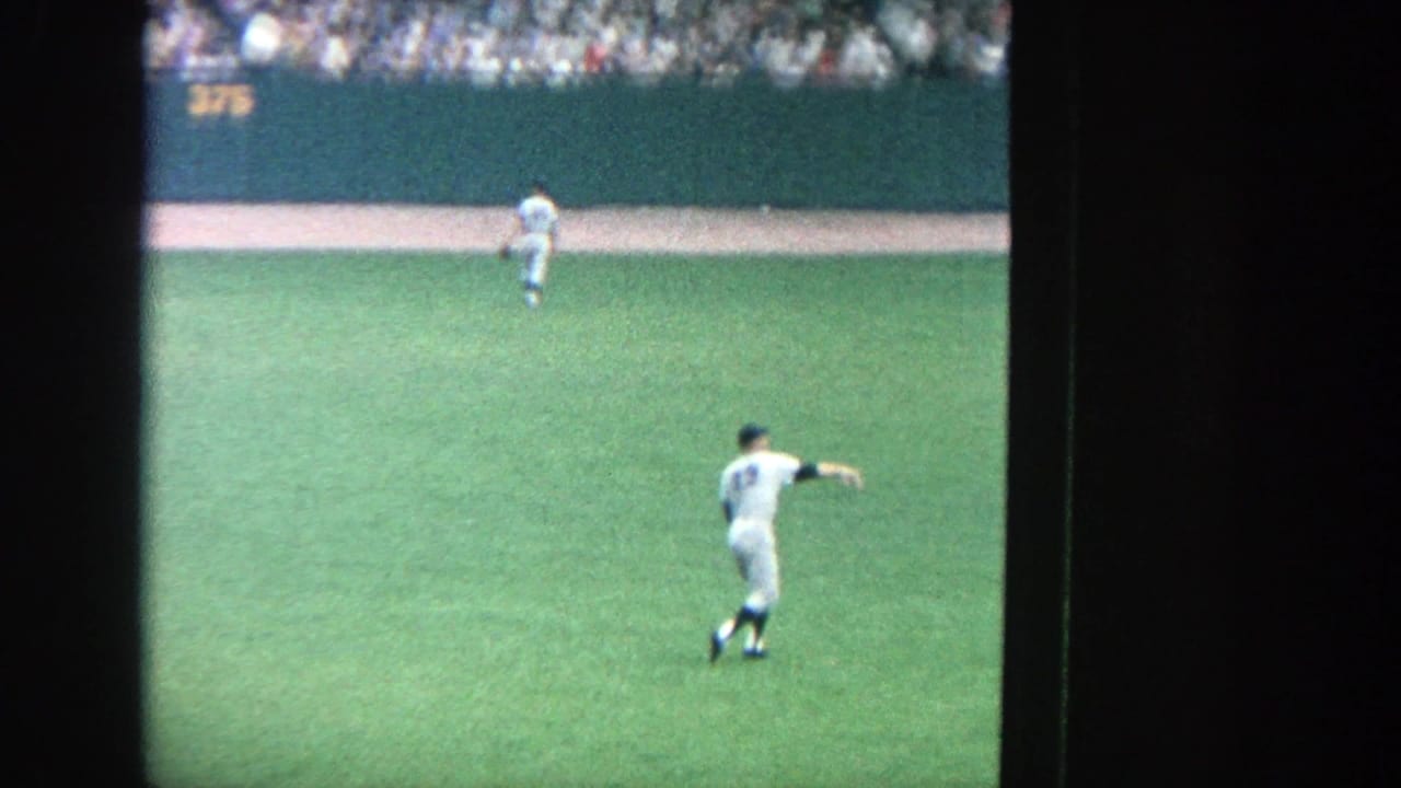 White-uniformed baseball player throwing or pointing in the outfield.