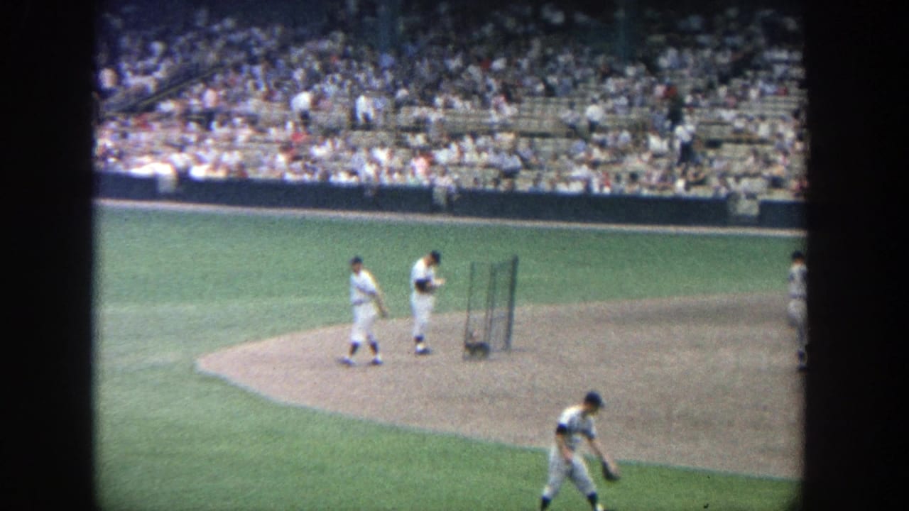 1964 Yankee Stadium home-movie view of players around the dirt infield with a large crowd in the stands behind them.