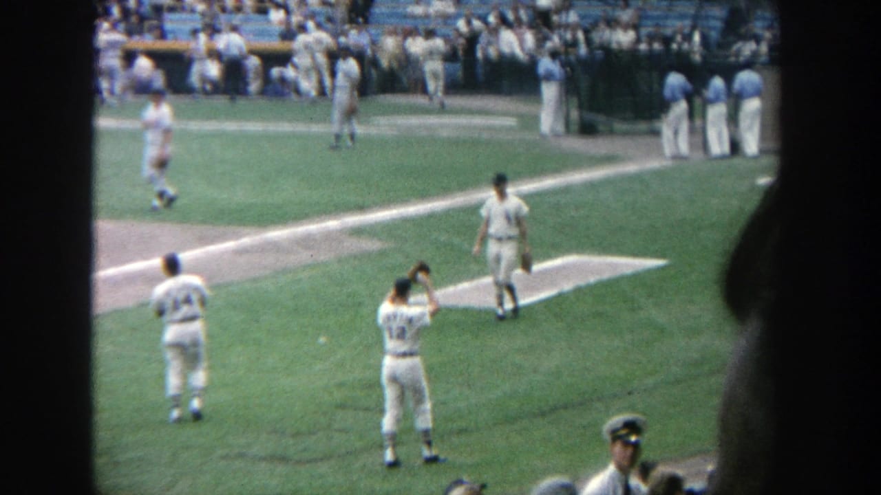 1964 Yankee Stadium home-movie view of uniformed players warming up near the foul line with spectators in the background.