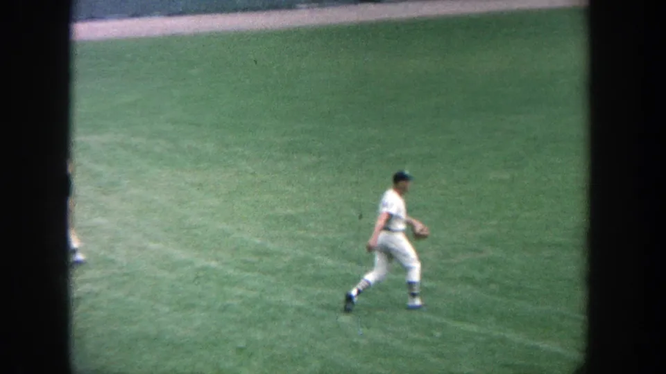 1964 Yankee Stadium frame showing a player crossing the outfield grass during pre-game practice.