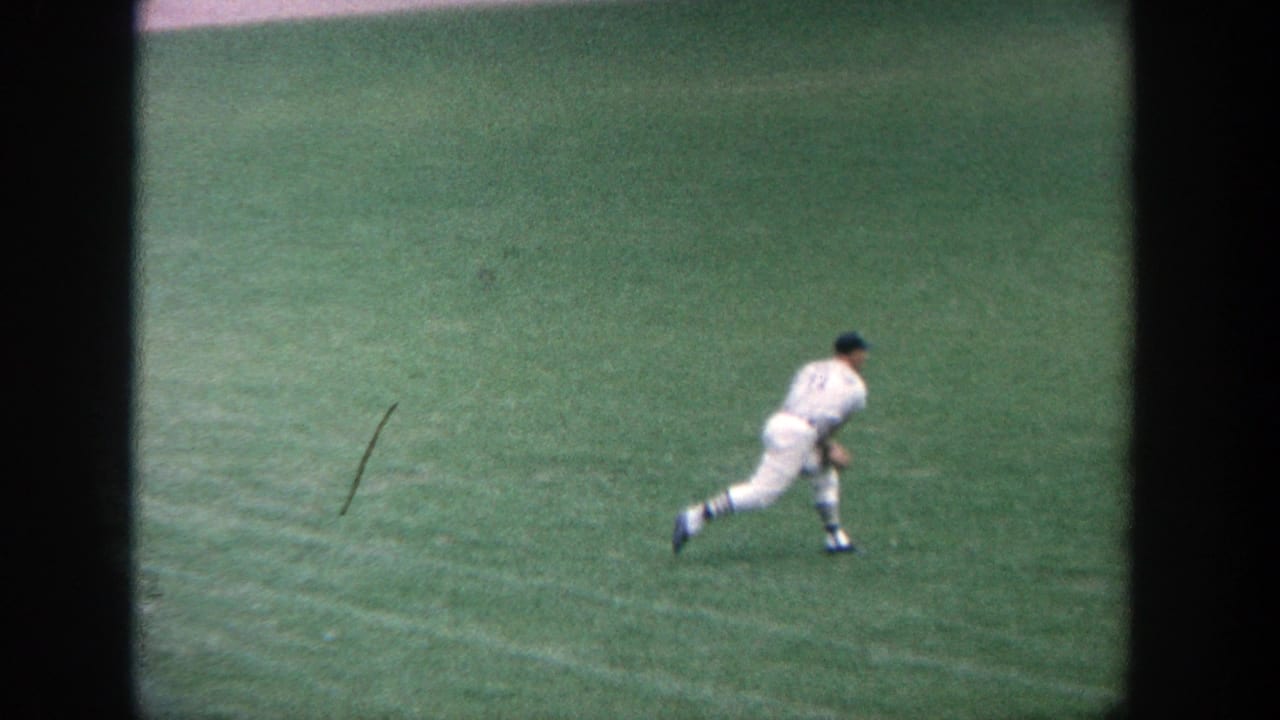 Baseball player in a white uniform runs across the green field.