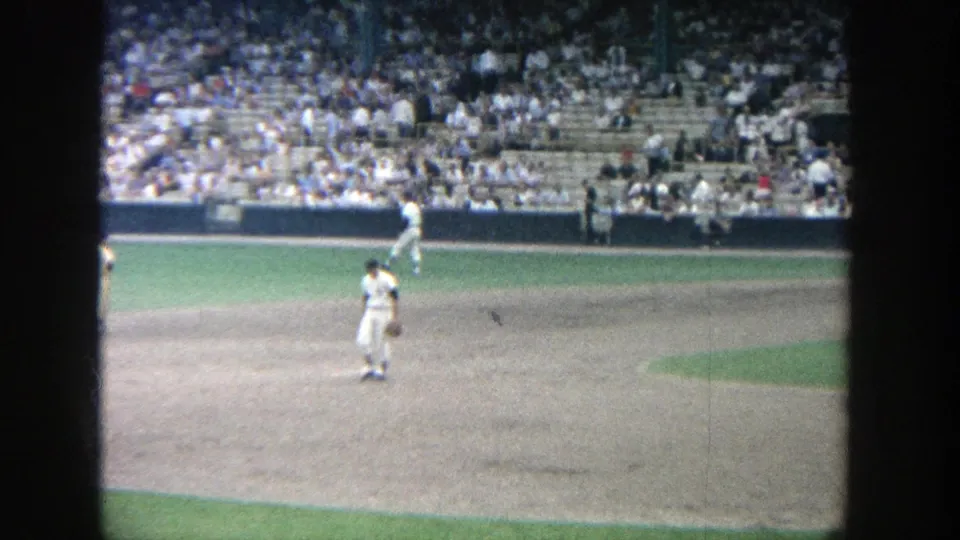 Late-frame 1964 Yankee Stadium view showing players spaced across the field, infield dirt, turf, and crowded seating.