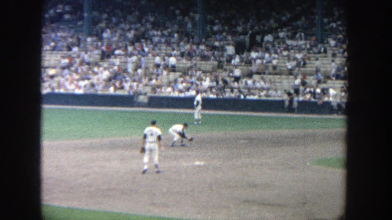 Baseball players on the infield with a large crowd seated behind them.