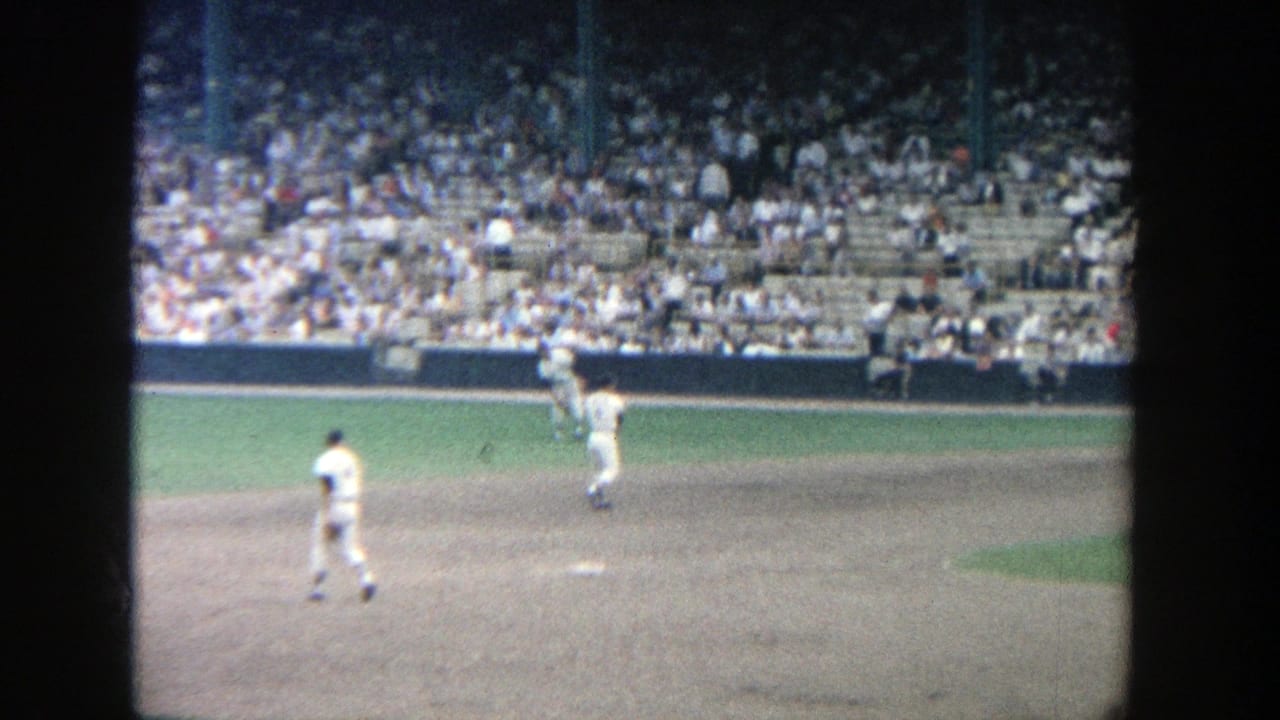 A baseball player throws on the infield while spectators watch from the stands.