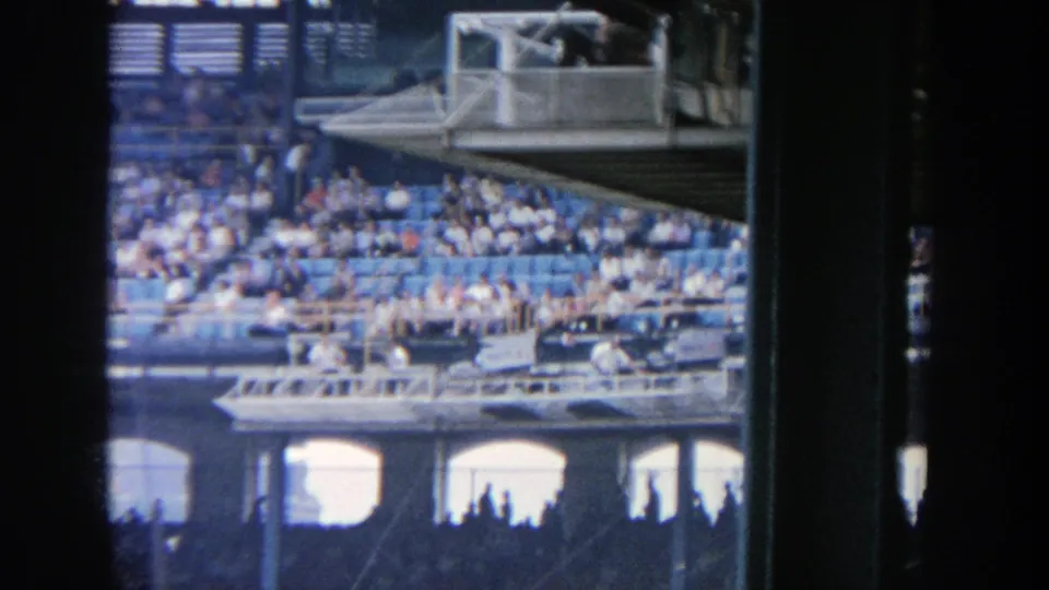 1964 Yankee Stadium frame focused on packed spectator seating and layered stadium railings in daylight.