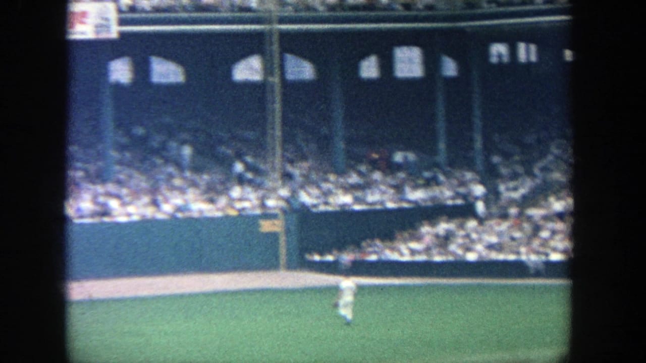 1964 Yankee Stadium 8mm frame showing the outfield, a distant baseball player, crowded stands, and upper stadium openings.