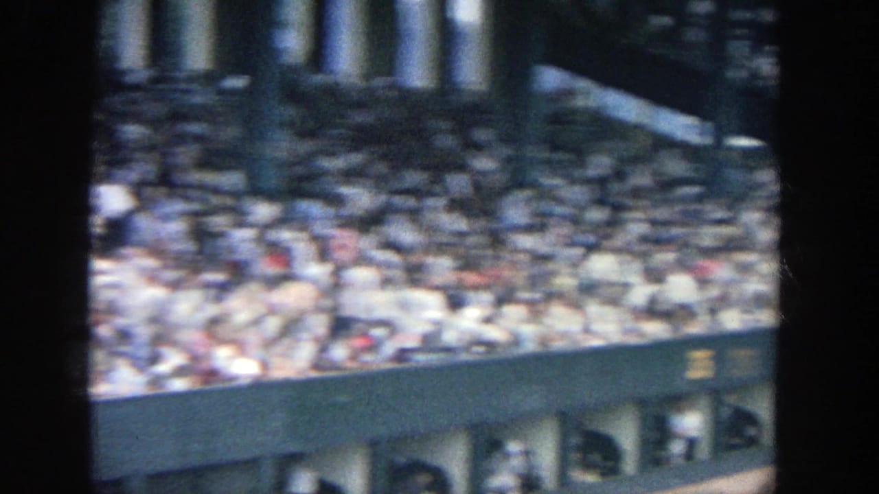 Upper stadium seating packed with spectators above green structural walls.