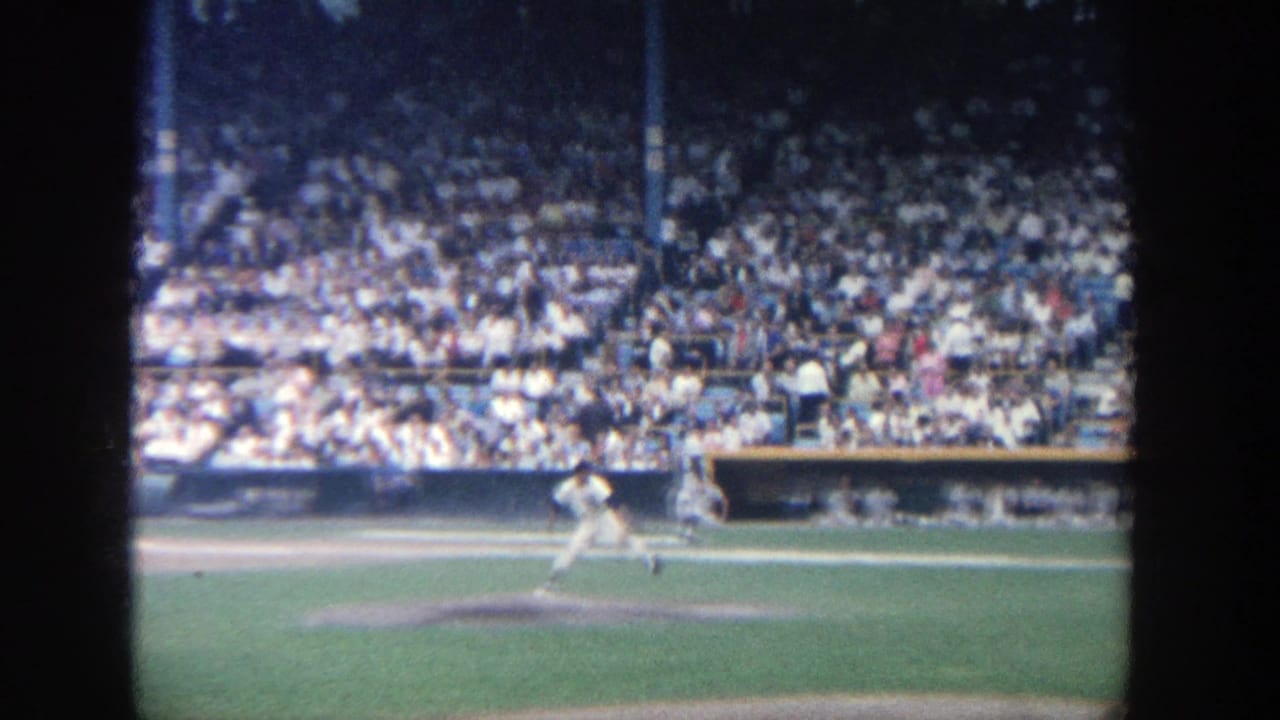 1964 8mm view at Yankee Stadium showing a pitcher preparing or moving through a throw before a large crowd.
