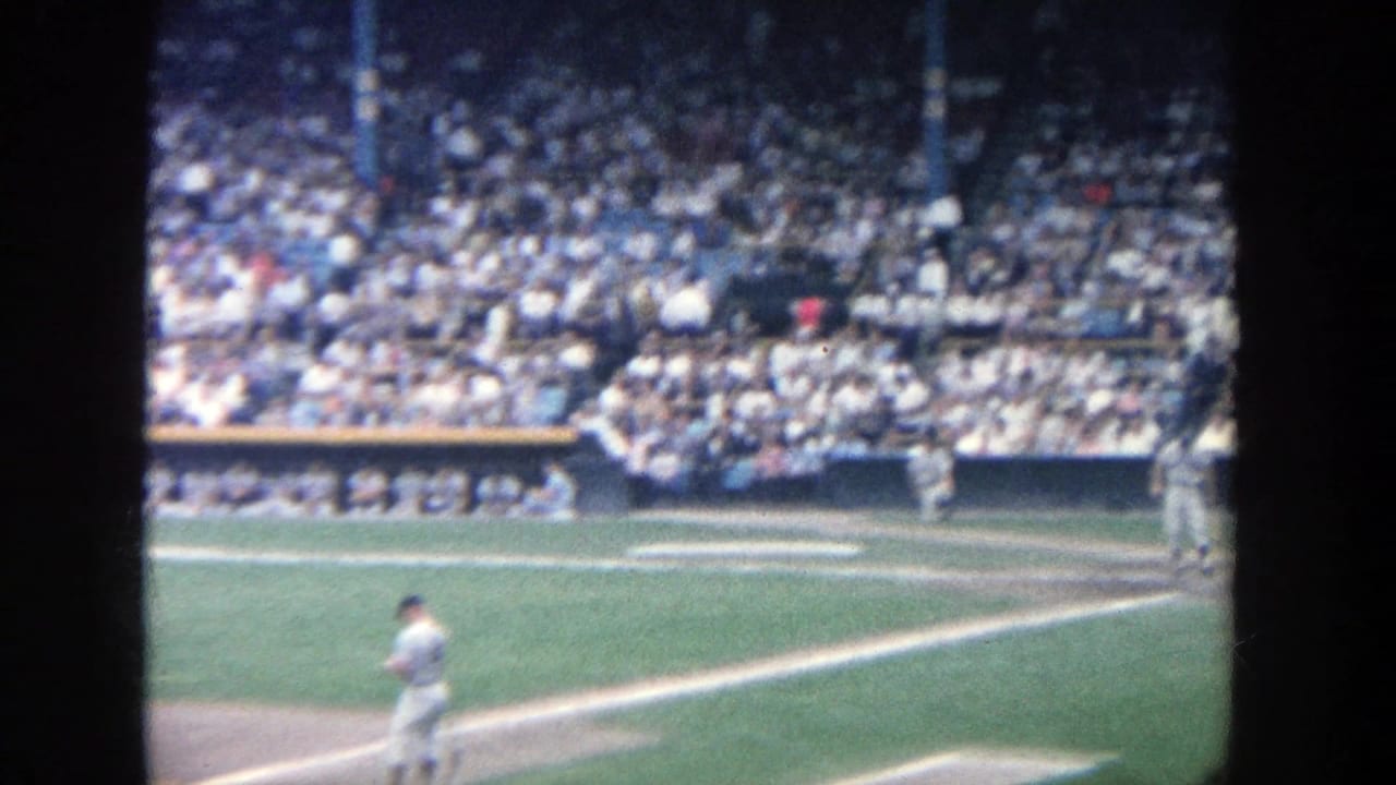 Baseball player crosses the infield while another player stands near the right side of the field.