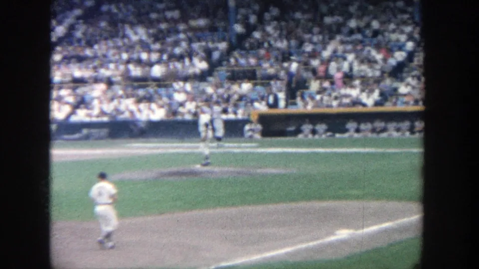 1964 Yankee Stadium frame showing the pitcher area, nearby infielders, and densely filled grandstands in soft 8mm color.