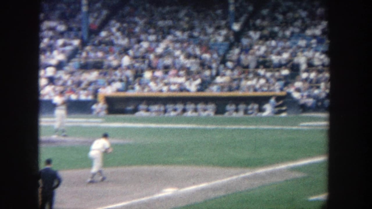 Pitcher on a baseball mound with crowded stadium stands behind him.