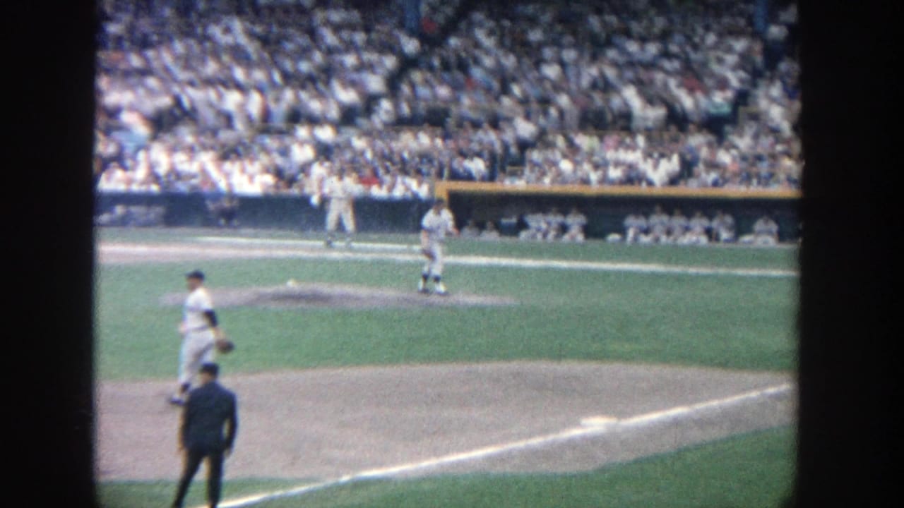 Baseball players on the field with a pitcher near the mound and a crowded stadium behind them.