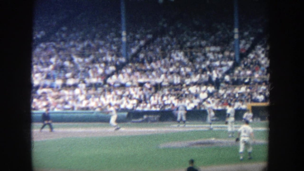 Baseball play near the infield with fielders and a large crowd in the stands.