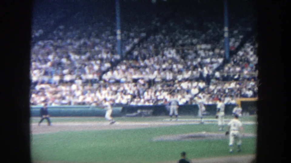 Spectator-shot 1964 Yankee Stadium baseball footage showing players spread around the infield before a packed grandstand.