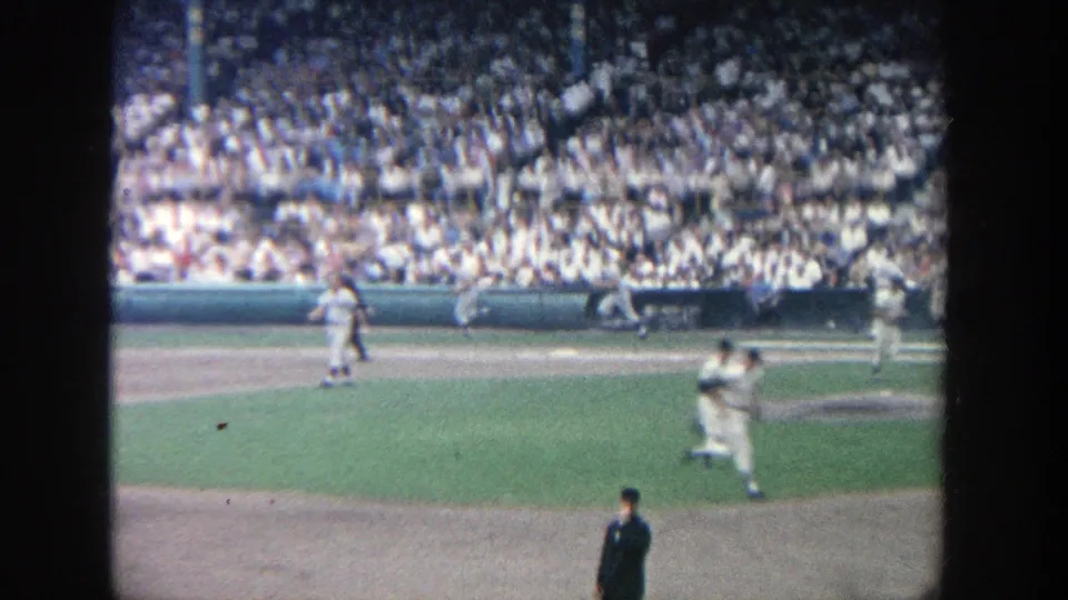 Visitor-shot 1964 baseball footage at Yankee Stadium, with a player in motion and a dense crowd in the background.