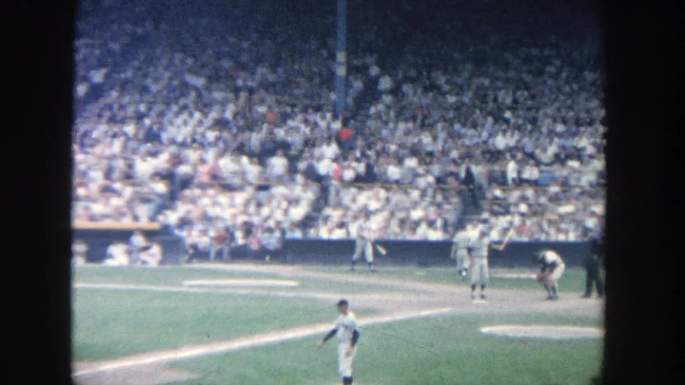 Wide 8mm view of the 1964 Yankee Stadium field, showing players spread across the diamond before a large crowd.