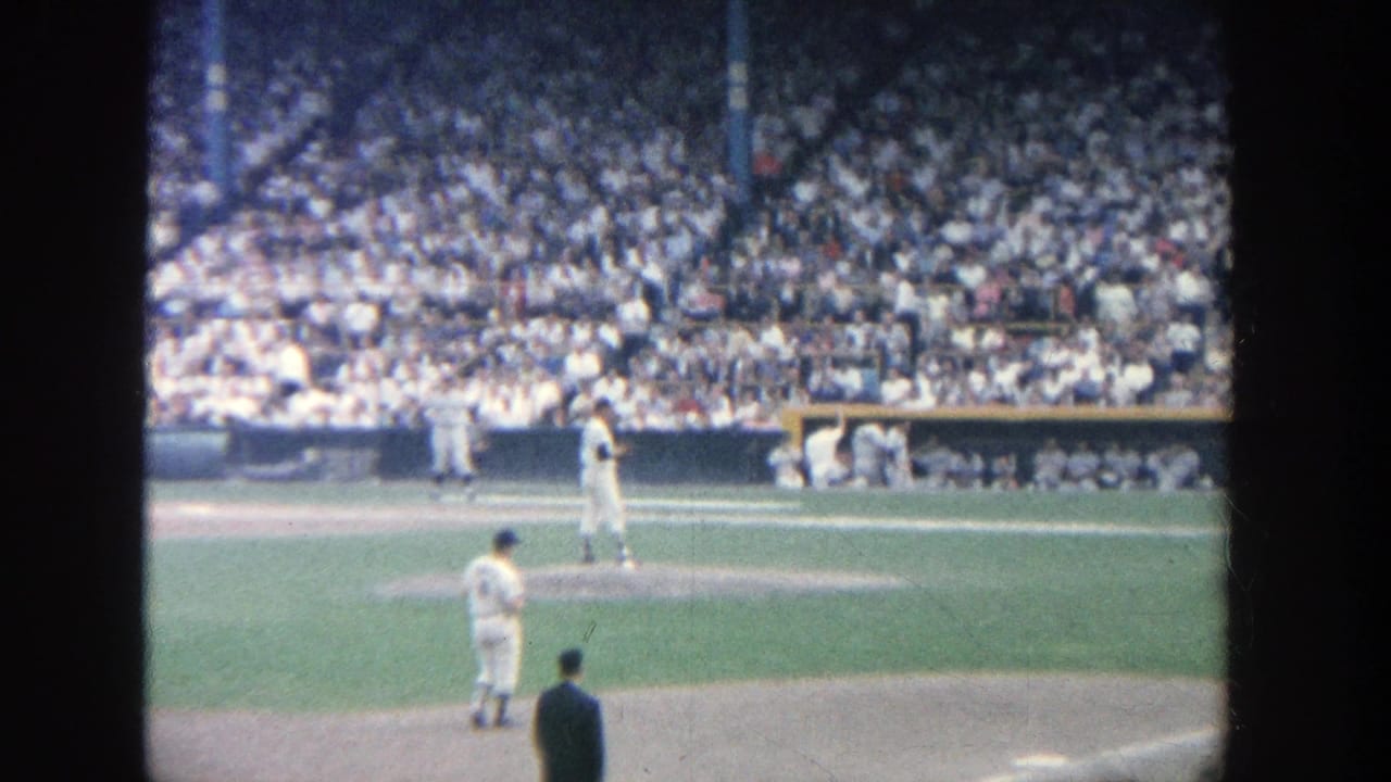 Pitcher on the mound with a batter near home plate and a crowded grandstand behind them.